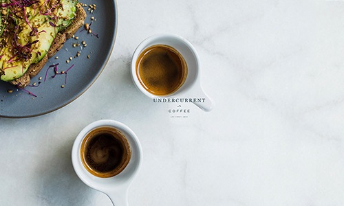 two coffee cups by a plate of food