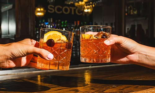 two people holding glasses of whiskey